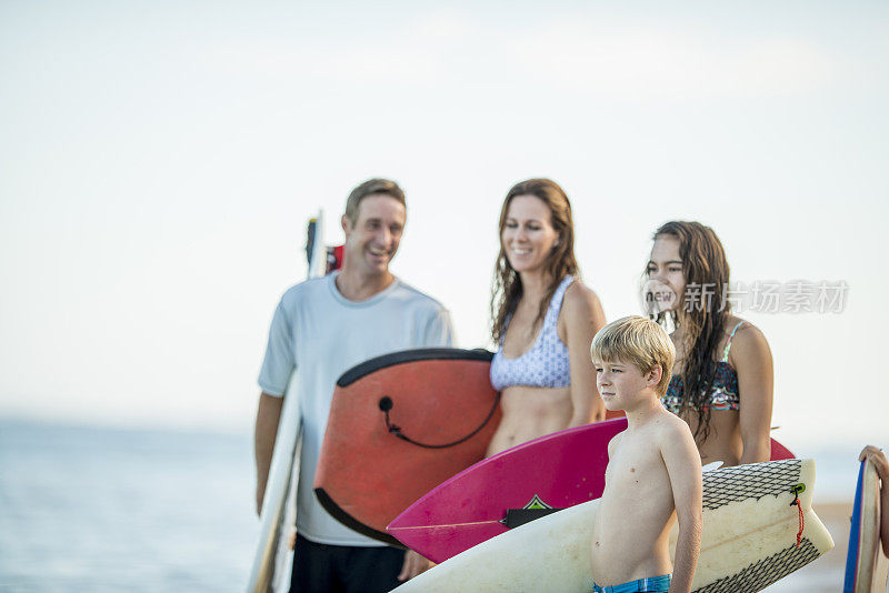 年轻的家庭在海滩上冲浪