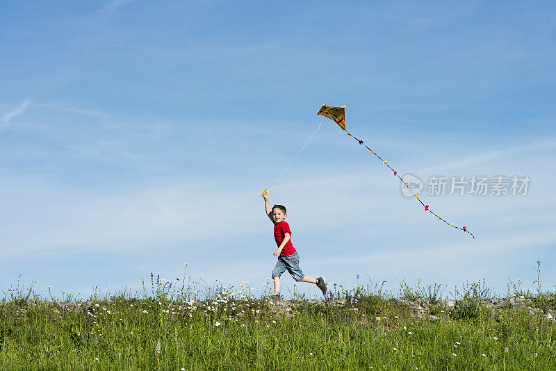 一个快乐的男孩在一个晴朗的日子里跑着放风筝