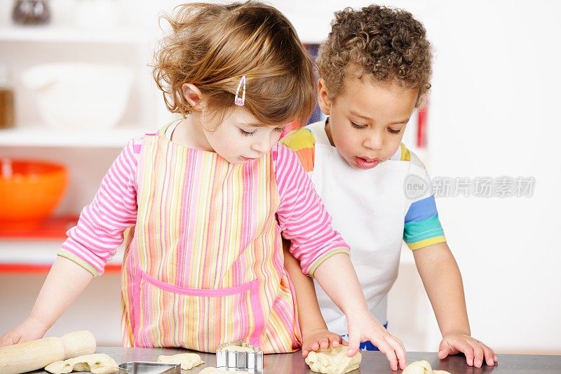 可爱的小女孩和男孩在厨房里准备生面团