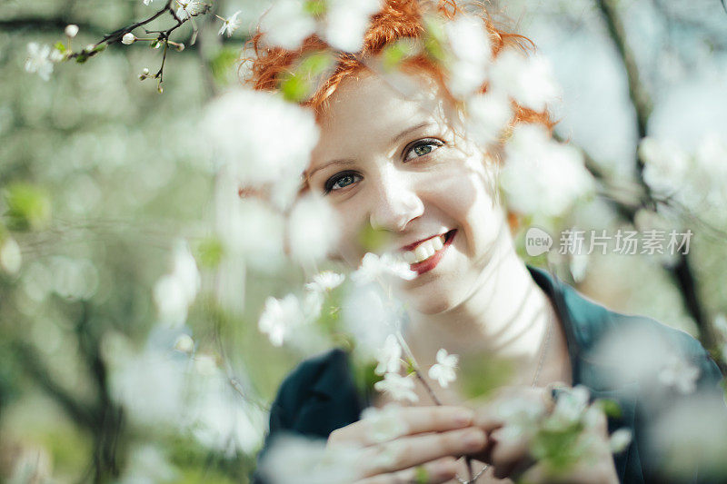 春天的肖像红发女孩在盛开的树木