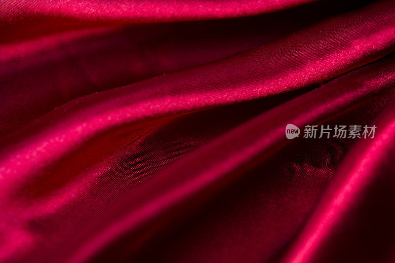 红色缎子或丝绸背景。织物上的波纹。