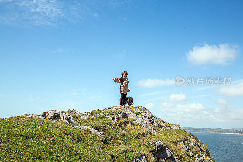 一个成熟的西班牙女人站在遥远的海岸岬角上