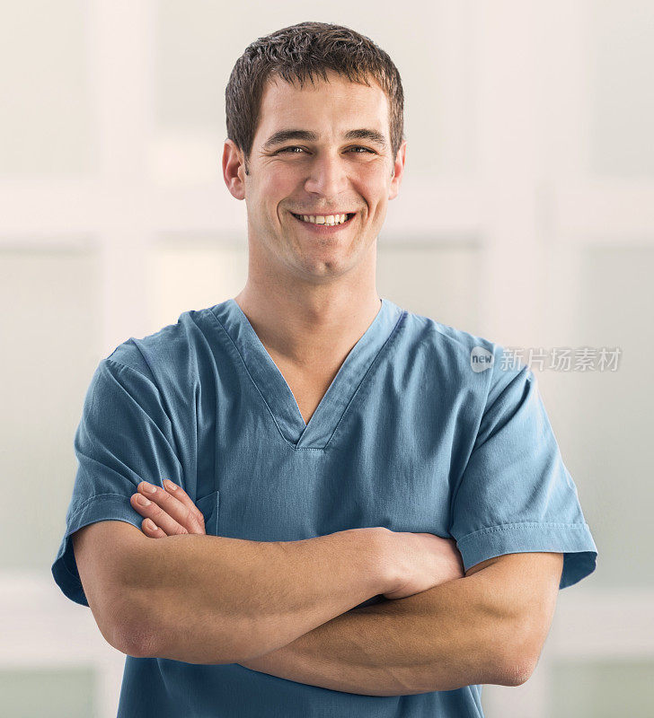 微笑的外科医生双臂交叉看着镜头。