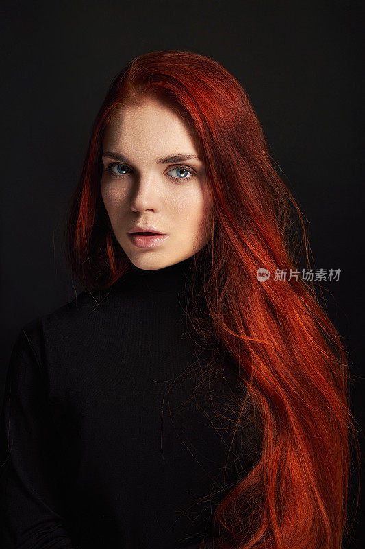 性感漂亮的长头发红发女孩。完美的女人肖像在黑色的背景。漂亮的头发和深邃的眼睛。自然美，清洁皮肤，面部护理和头发。强壮而浓密的头发。花