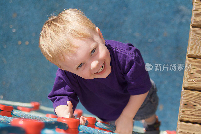 男孩在爬游乐场的绳梯时抬头看