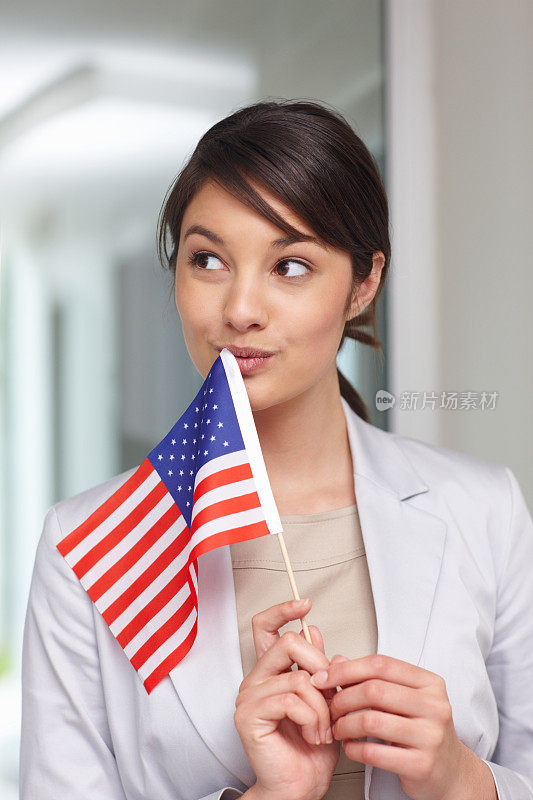 年轻的爱国女性举着美国国旗，陷入了沉思