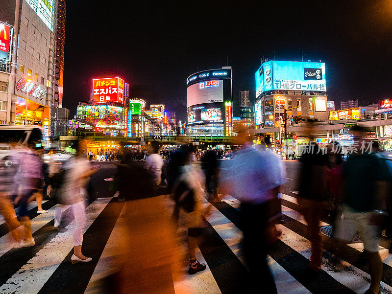 在日本东京，人们正在穿过新宿的十字路口