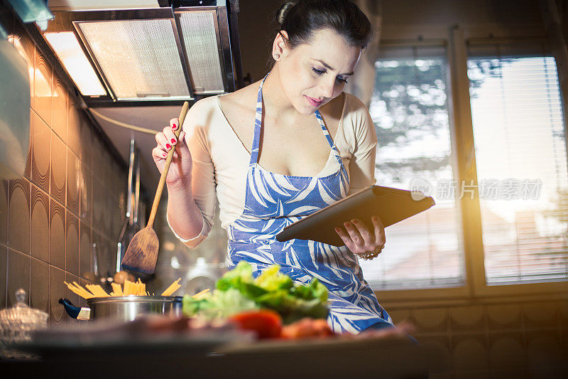 美丽的年轻女子在数字平板电脑上阅读食谱