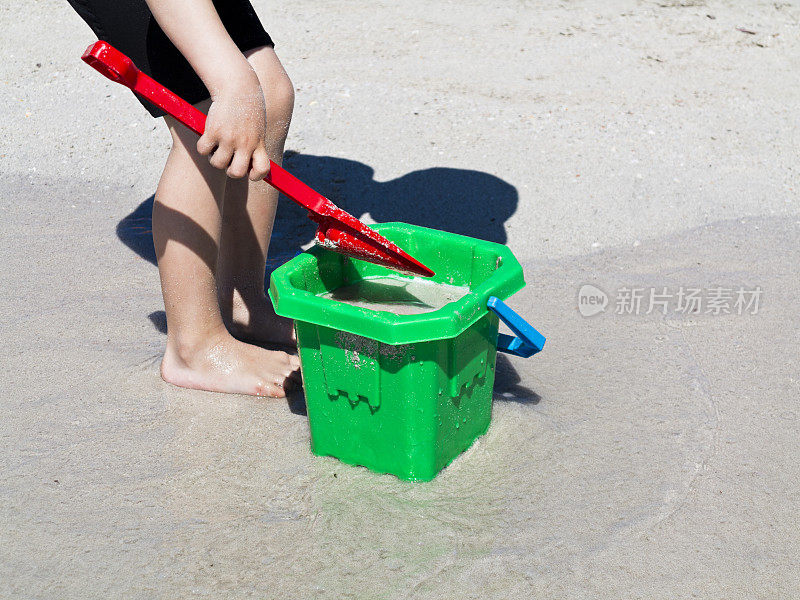 孩子们在海滩上玩水桶和铲子。