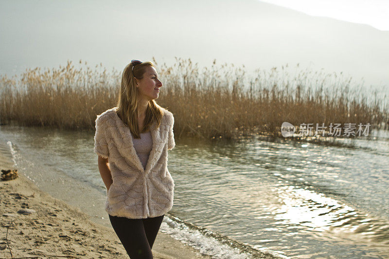 一个年轻女子独自在海滩上微笑着走着