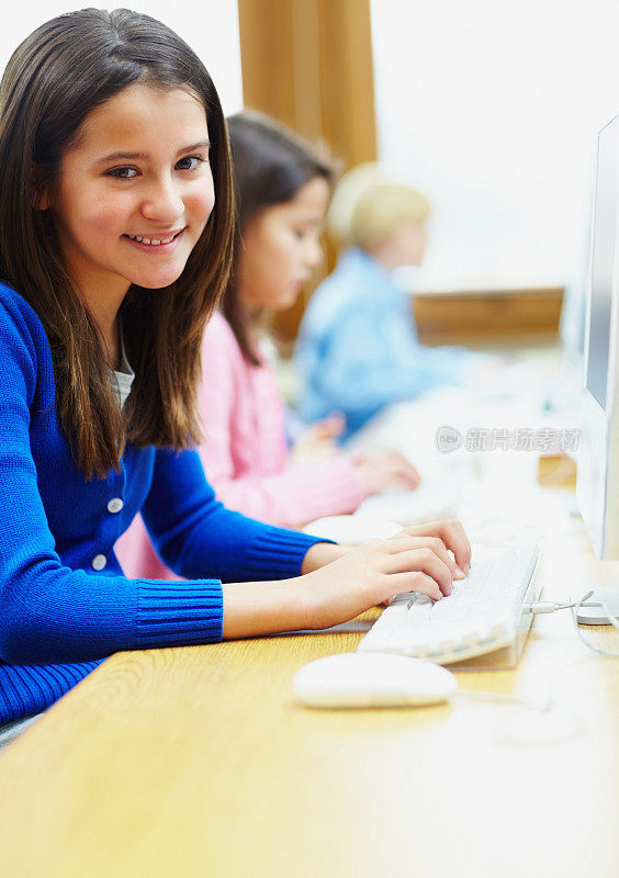 一个微笑的女孩在电脑室的肖像