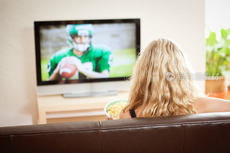 年轻女子在家看电视直播体育足球