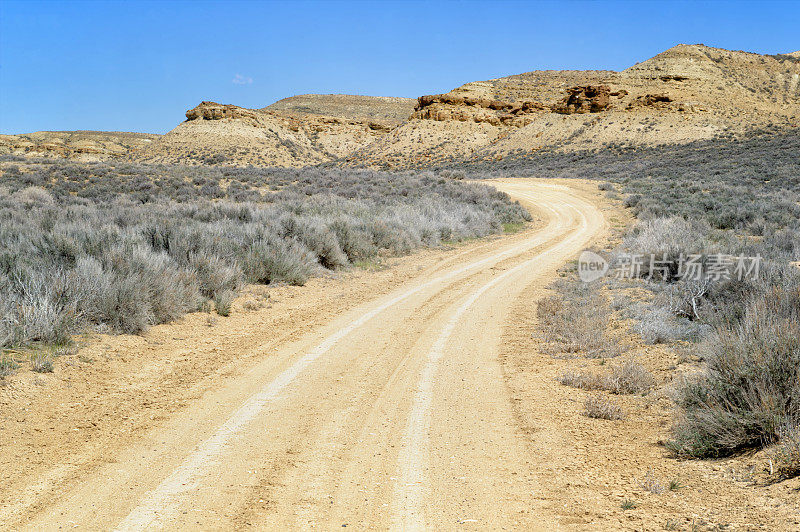 沙漠道路与岩石悬崖和山艾树，科罗拉多州，美国