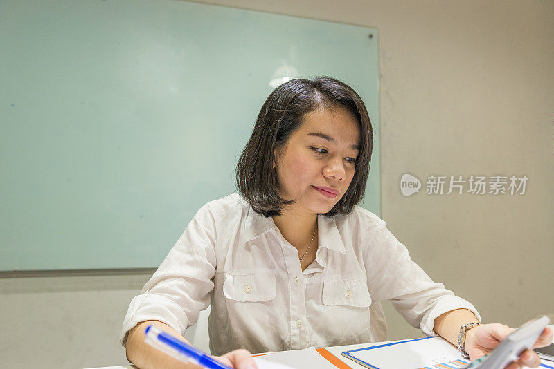 女商人一边工作一边用智能手机看信息