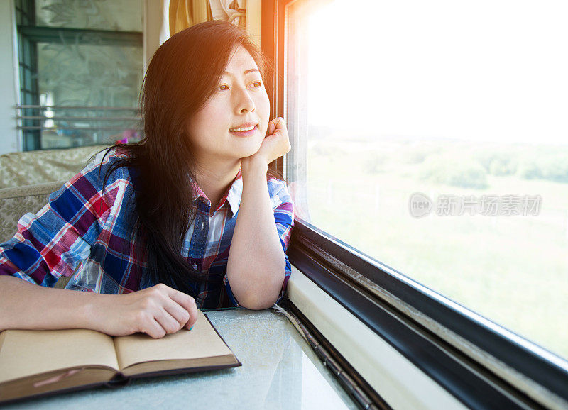 一个年轻的亚洲女人在火车上看书