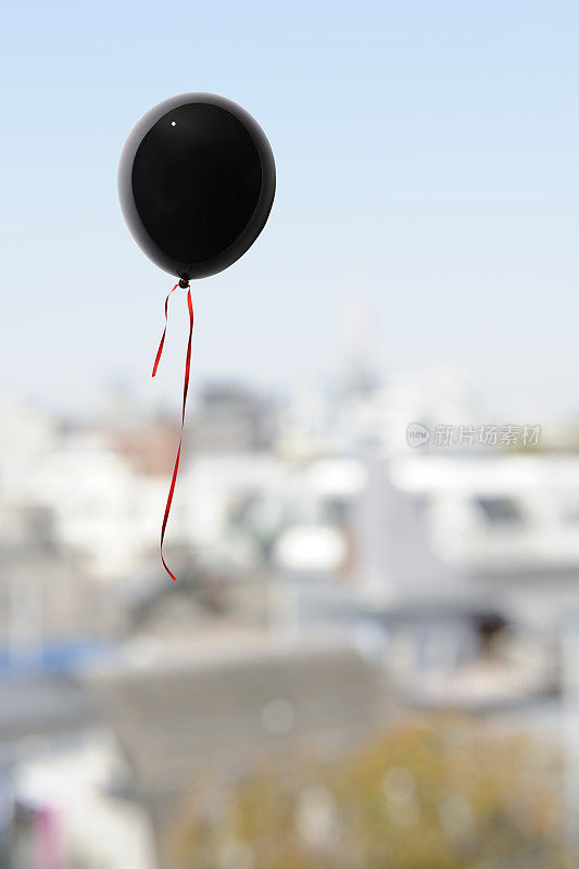 一个黑色的气球漂浮在小镇上