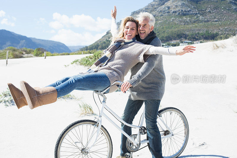 一对无忧无虑的夫妇在海滩上骑自行车