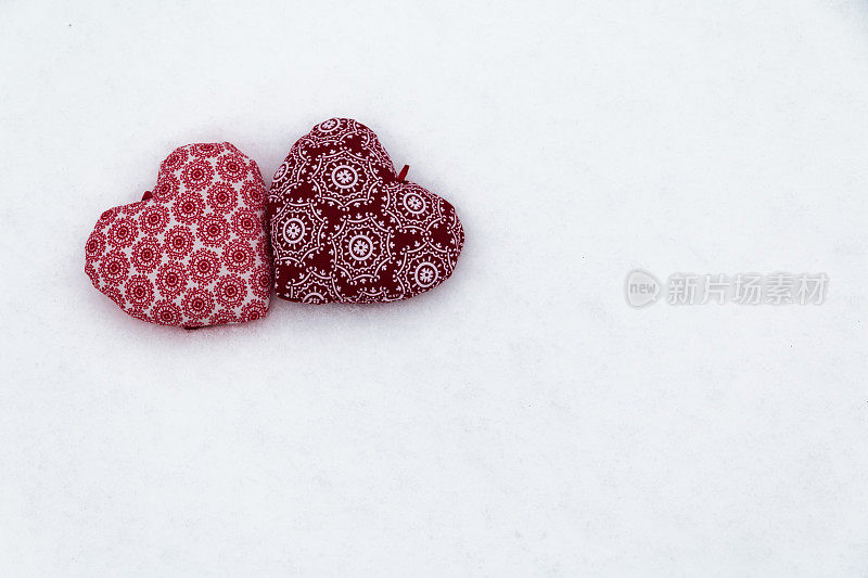 雪中两颗红心在一起。爱的象征。