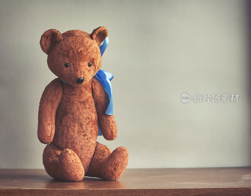 一个带着蓝色蝴蝶结的破旧的玩具熊