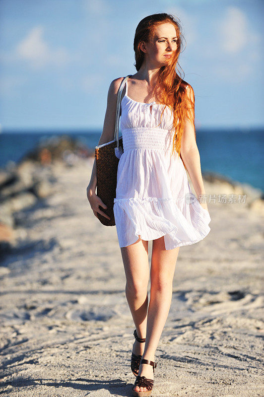 沙滩上穿着白色背心裙的年轻女子