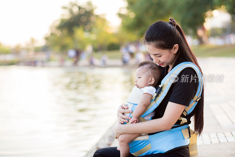 一位年轻的亚洲母亲和她的男婴在婴儿背带里
