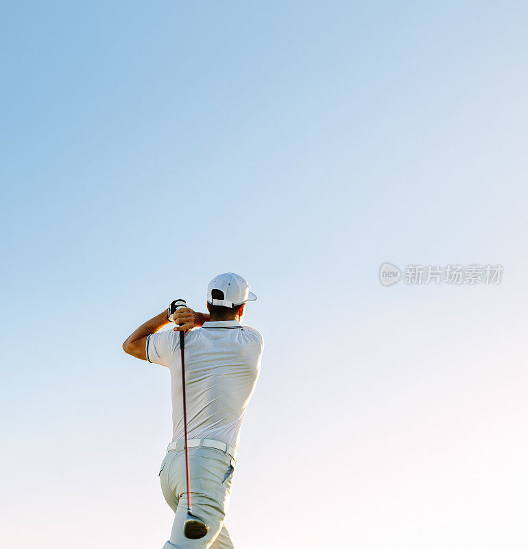 晴朗的天空下挥舞着高尔夫球杆的男子