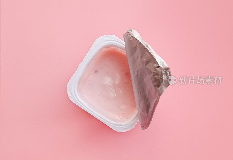 打开的草莓酸奶或布丁放在白色塑料杯中，平整