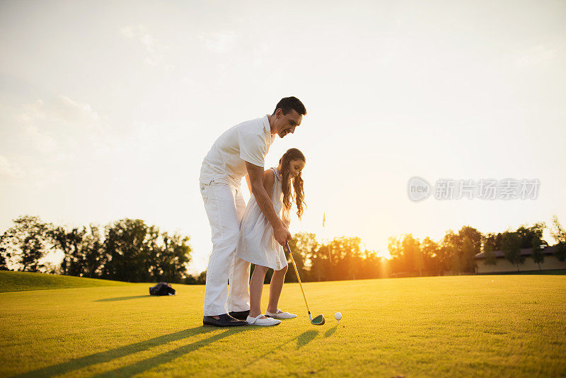 一个女孩和她的父亲学打高尔夫球