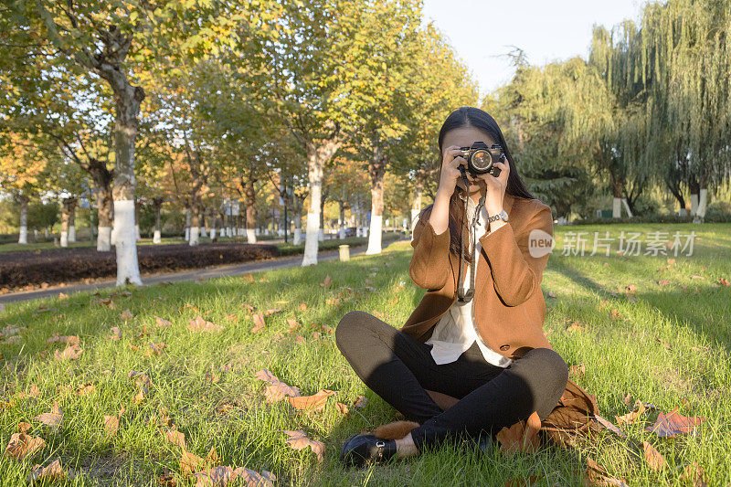 一个女人在公园里用相机拍照