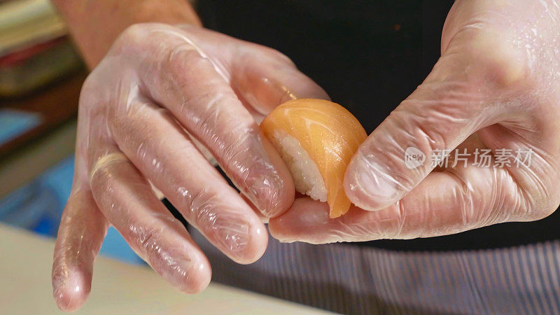 大厨用手制作三文鱼寿司的微距镜头。