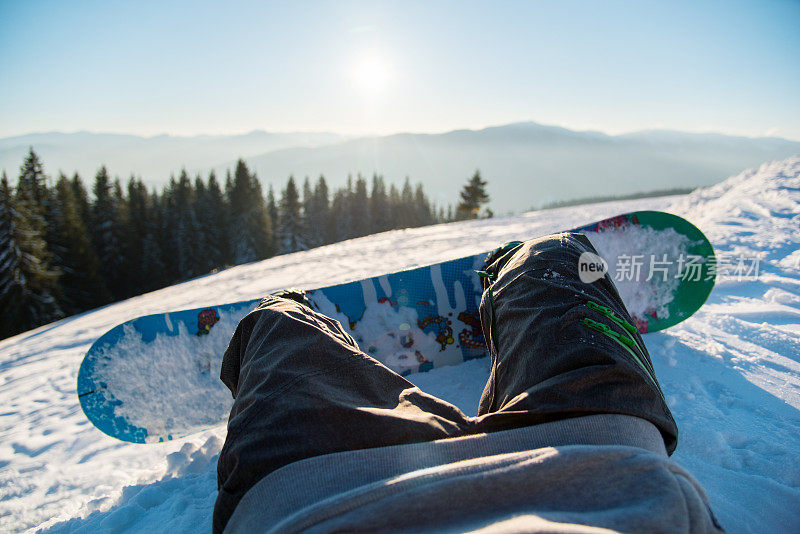 视角拍摄的一个滑雪者躺在雪坡上的早晨，放松后滑雪，享受冬季山的惊人的观点概念