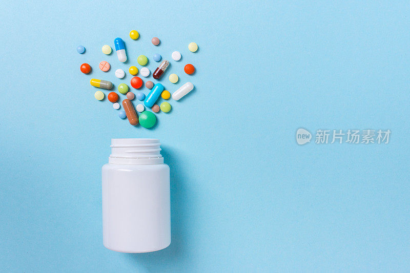 各种药物，药片，胶囊和瓶子在蓝色的背景。文本复制空间
