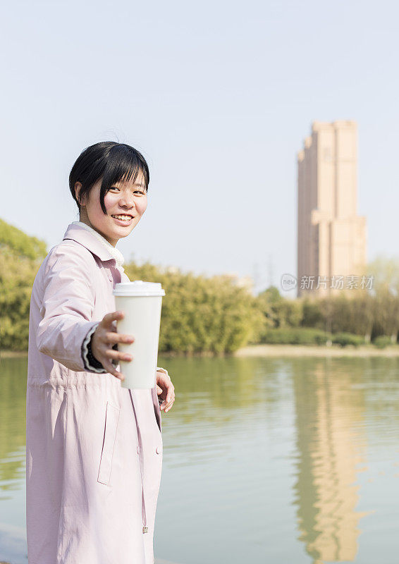 年轻女性拿着一次性杯子在草坪上