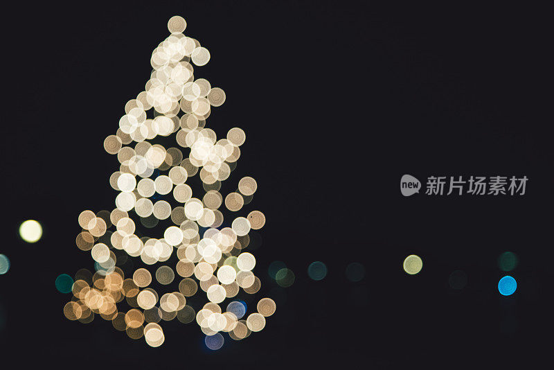在室外的一棵大圣诞树上，抽象出聚光灯。理想作为背景或设计元素。