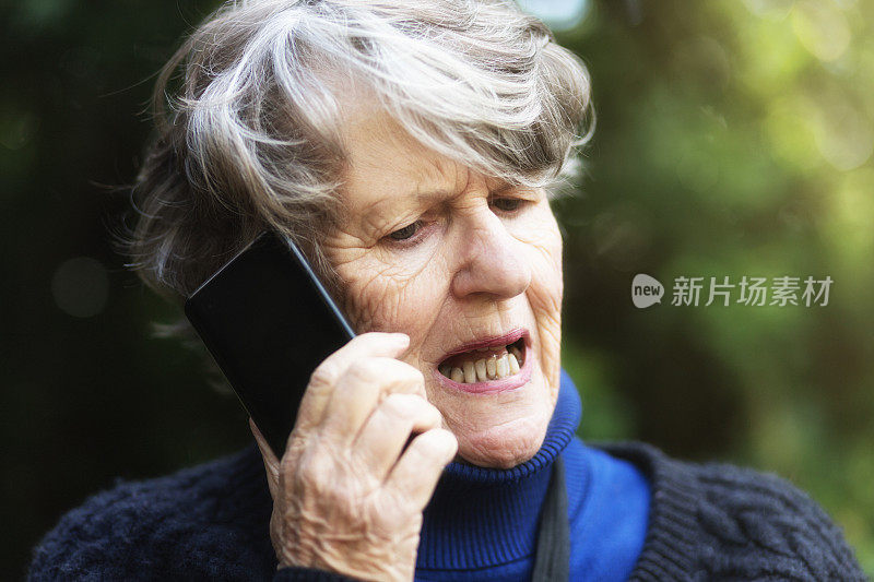 在户外拿着手机的老女人生气地说话