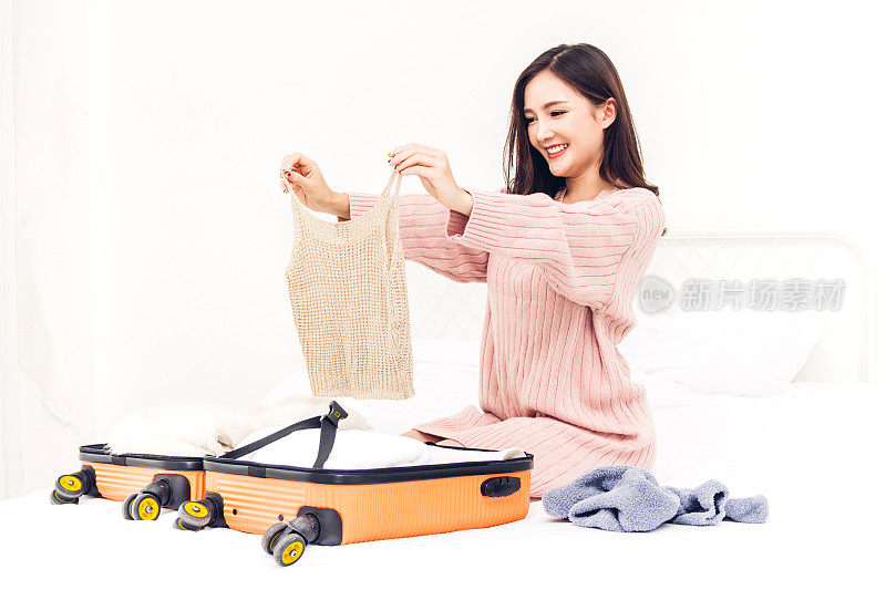 女人打包一个手提箱行李和背包在家里旅行。节日假期的概念