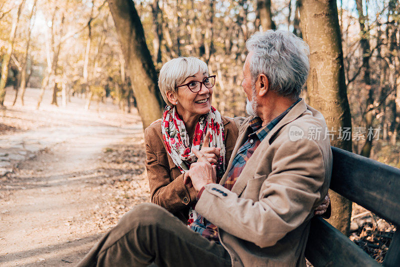 一对微笑的老夫妇坐在公园的长椅上