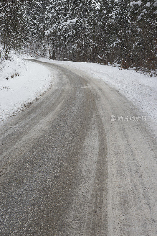 冰雪弯弯曲曲的道路穿过白雪覆盖的山林