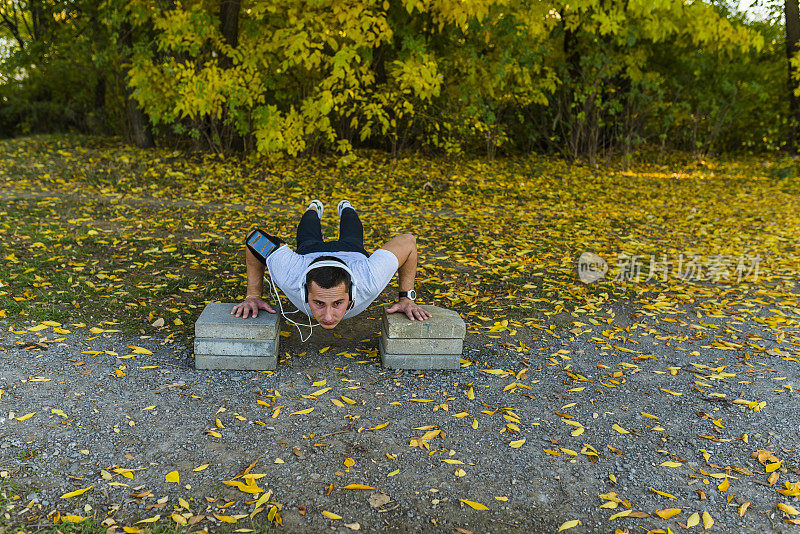 在公园里做俯卧撑的年轻运动员
