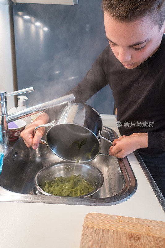 十几岁的男孩正在烹饪菠菜绿意面