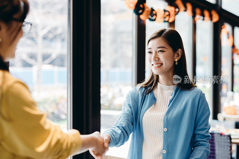 两个亚洲女商人见面握手。