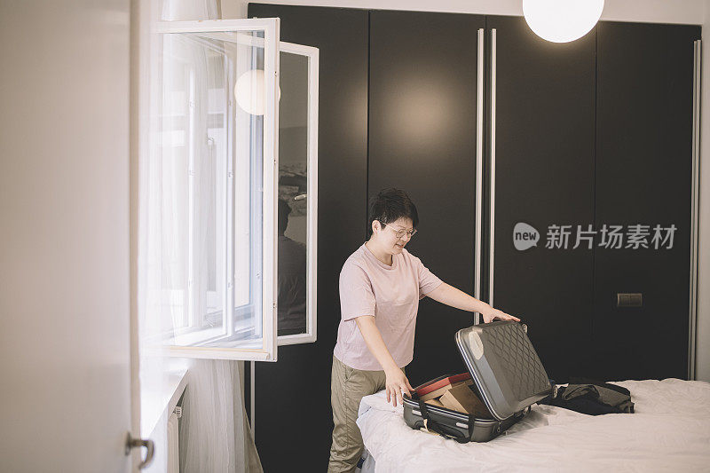 一名亚洲华裔女性在旅行前在房间里打包行李