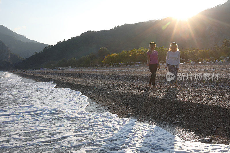 日出时，妇女们沿着海滩散步