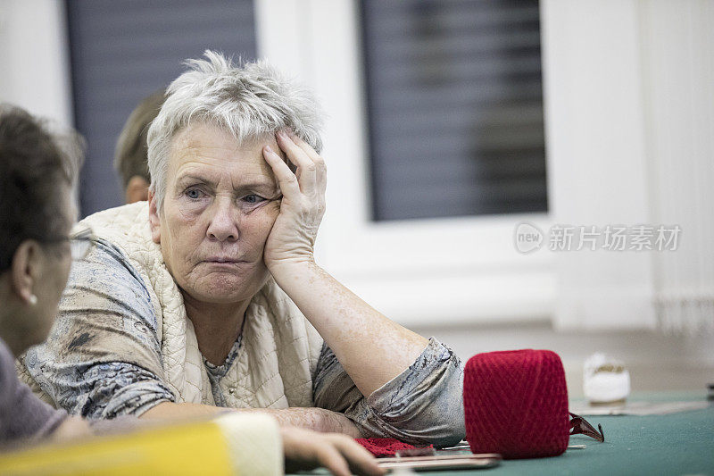 疲惫的老年妇女在老年社交聚会上听朋友讲话