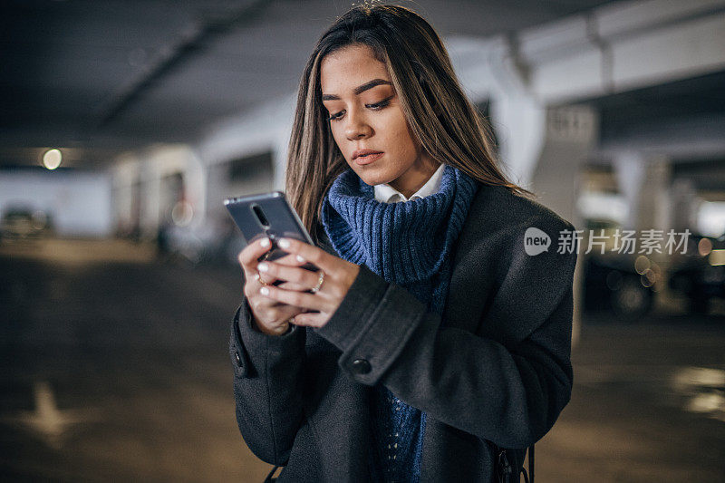 年轻女子在地下车库使用手机