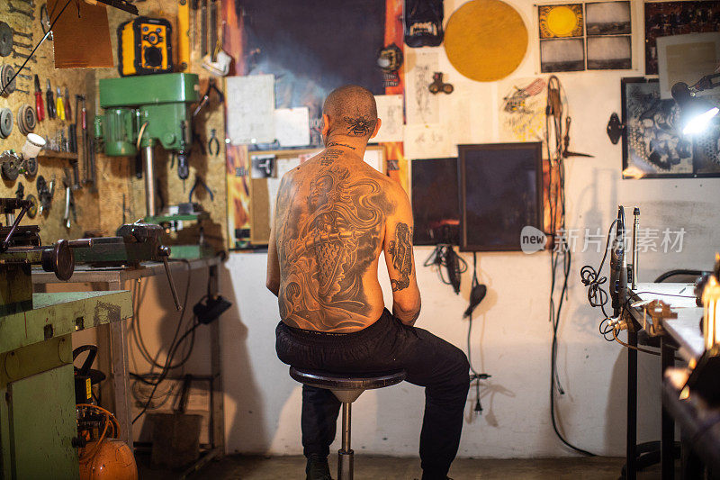 纹身艺术家与纹身头坐在他的工作室，看他的艺术作品