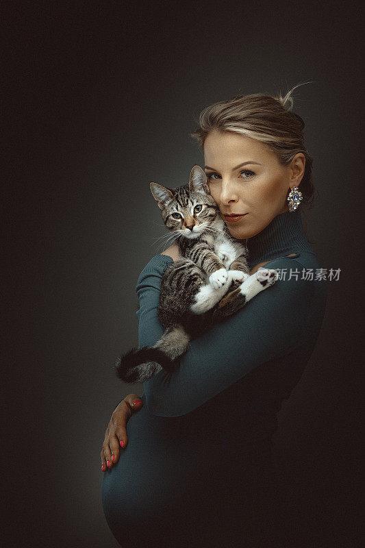 年轻怀孕有吸引力的女人抱着可爱的小猫