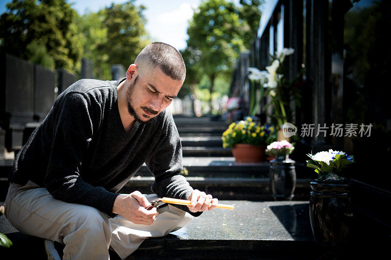 成熟的男人会因为失去最亲密的人而伤心。在墓地上拿着蜡烛的情绪紧张的男人