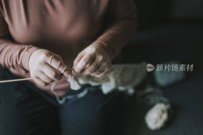 一个亚洲华人中年妇女在客厅编织在她的空闲时间休闲活动