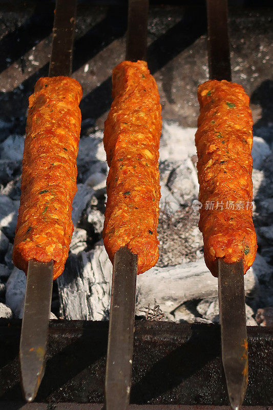 烤肉串的形象，烧烤，腌制的肉块在金属串上烤，躺在热的木炭灰烬上